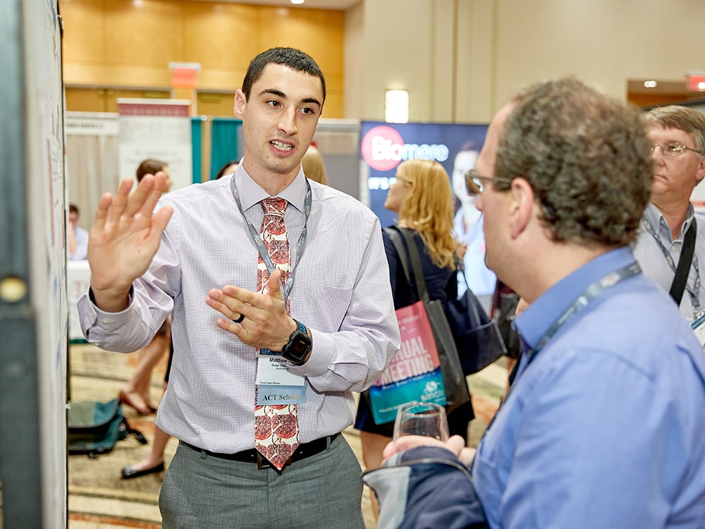 2 attendees discussing a poster